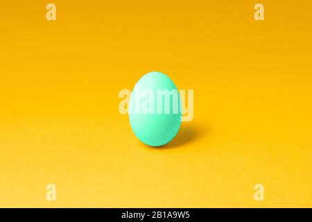one pastel mint color egg in center on yellow background. easter concept design Stock Photo