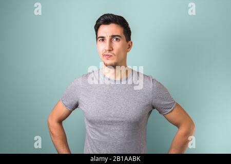 handsome man in grey t-shirt thinking or having doubts on light-coloured background Stock Photo