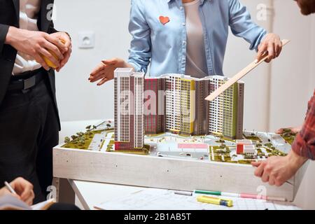 woman pointing with ruler to a new complex of building, introducing colleagues with plan of developing new area, distruct, close up cropped photo.focu Stock Photo