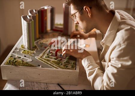 young handsome man developing area, district, close up side view photo. architect working with a ruler and a modele. Stock Photo