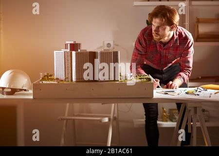 hardworking ambitious man is concentrated on drawing a sketch, building on the blueprint, paper, close up photo. guy making notes and looking at the m Stock Photo