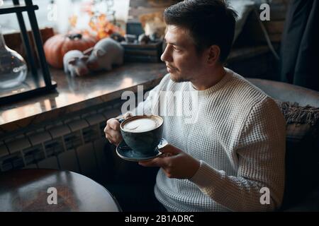 young pleasant guy having coffee break after work, enjoyment concept. close up side view photo. free time, lifestyle, leisure Stock Photo