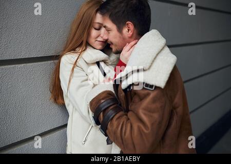 young man and woman in stylish warm clothes express tenderness, warm feeling and emotion. close up side view photo. courtship. loverbirds spending tim Stock Photo