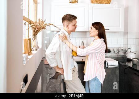 Couple talking and drinking tea in their kitchen, close up side view photo. love, warm tender relationship, friendship, relationship. Stock Photo