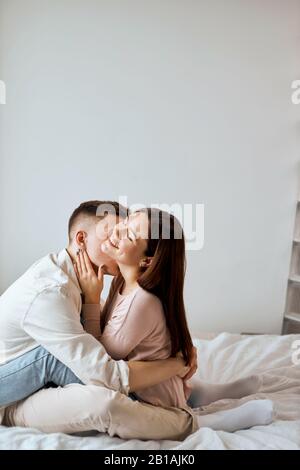 passionate couple in casual clothes having fun in the bedroom, man adores her girlfriend, kissing her on her neck. close up photo. I love you, you are Stock Photo