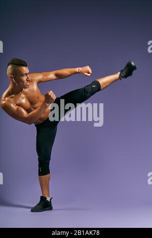 Man biting ips, training taekwondo, kickboxing at sport center Isolated on blue background, full length photo, isolated blue, studio shot, motivation, Stock Photo