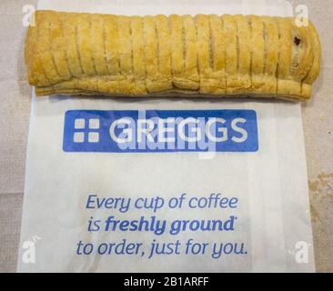 Greggs sausage roll on Greggs takeaway bag. Meat wrapped in layers of crisp  by Greggs bake store Stock Photo - Alamy