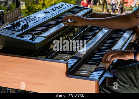 A closeup and side view with selective focus on the hands of a man playing a two tier electronic synthesizer keyboard, on stage at earth festival Stock Photo