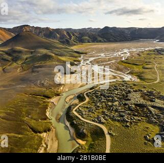 Majestic drone view of curvy road and riverbed near stony hills on cloudy day in Iceland Stock Photo