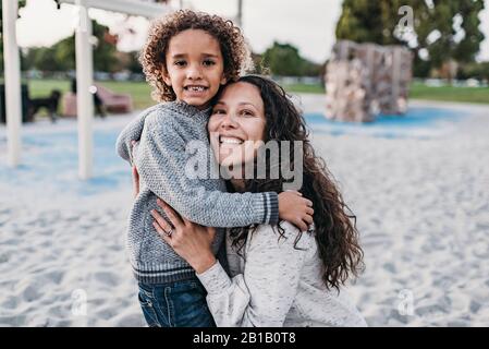 Close up portrait of mother and son smiling on playgroung at dusk Stock Photo