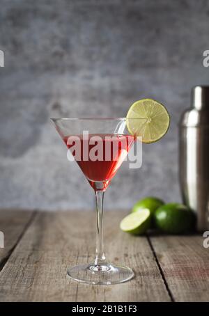 Close up of cosmopolitan martini drink and shaker on wood table.
