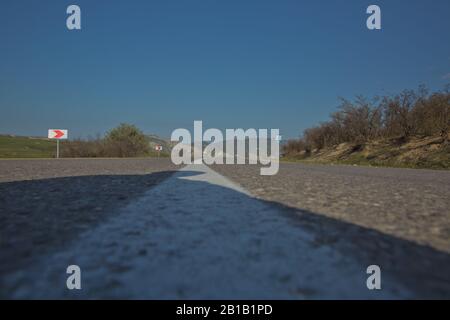 An empty road with single solid white line road marking. Background photo in perspective with selective focus . Red road sign . Asphalt road with Stock Photo