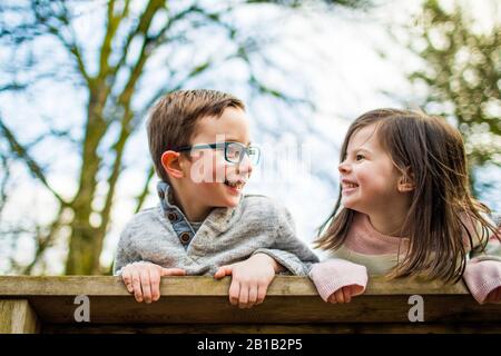 Playful portrait of boy and girl on railing. Stock Photo