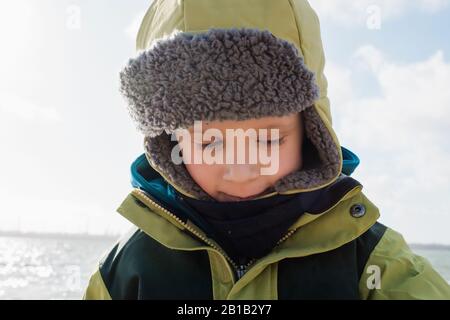 portrait of a young boy wrapped up warm at the beach in winter