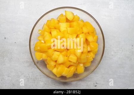 Sliced peach in a glass plate on a gray background with marble cracks and specks. The concept of healthy nutrition, summer mood. Stock photo for web, print, background and wallpaper. Stock Photo