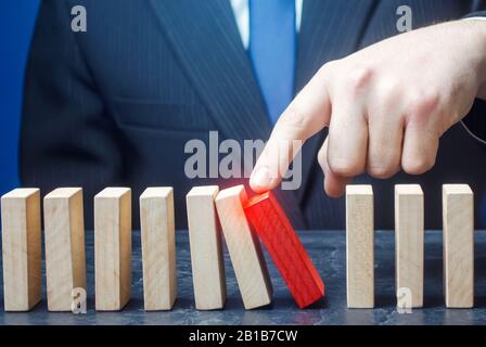 Businessman starts the process of falling dominoes. Correction of errors malfunctions. Implementation of plans. Starting work after stopping. Continua Stock Photo