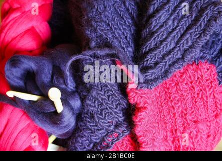 Closeup of knitted colorful purple pink blanket, ball of merino wool, knitting needles Stock Photo