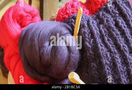 Closeup of knitted colorful purple pink blanket, ball of merino wool, knitting needles Stock Photo