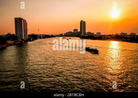 Scene of the beautiful sights seeing of Chao Phraya River with long tail boat and building around. Experience the exotic Bangkok by sunset .beautiful Stock Photo