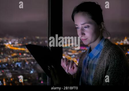 Woman using black digital tablet at night Stock Photo