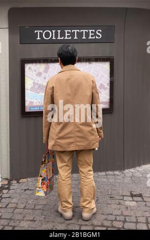man reading map on toilettes building Saint Germain en Laye Paris France Stock Photo