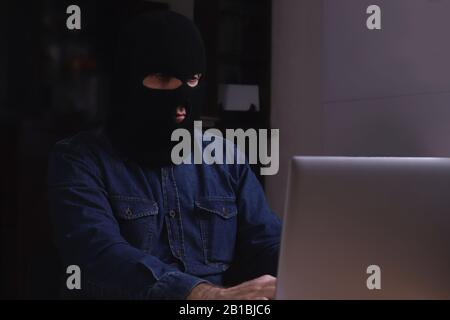 Thief stealing data from laptop Stock Photo