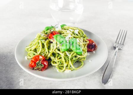 Pasta spaghetti with homemade pesto sauce, roasted tomatoes and fresh basil leaves, vegetarian food Stock Photo