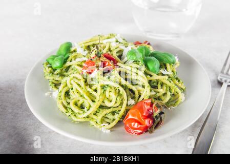 Pasta spaghetti with homemade pesto sauce, roasted tomatoes and fresh basil leaves, vegetarian food Stock Photo