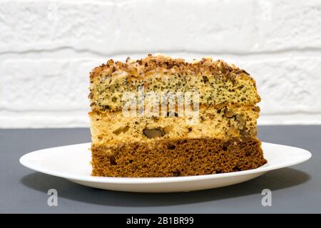 Chocolate cake with a separate piece on a white plate on a gray background. Stock Photo