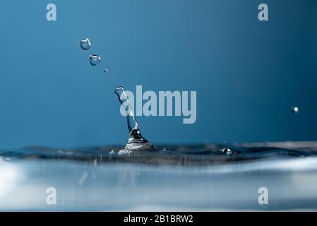 Water Drop falling making droplet splash and waves clean and fresh symbol. Stock Photo