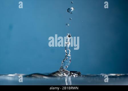 Water Drop falling making droplet splash and waves clean and fresh symbol. Stock Photo