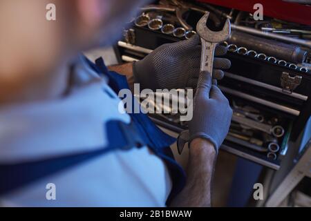 High angle close up of car mechanic holding wrench while choosing tools in garage shop, copy space Stock Photo