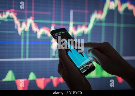 Businessman checking stock market data. He using a mobile phone. Analysis economy data on forex earn graph. Stock Photo