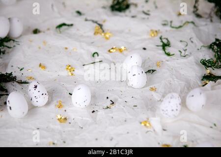Easter background. White eggs on creased paper background with golden scraps. Abstract decoration, seasonal arrangement. Stock Photo