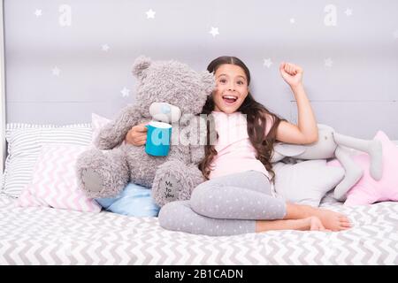 Little child hold mug. Girl in pajamas drinking tea. Relaxation before sleep. Drinking milk just before bed. Bedtime beverage. Hot milk before sleep. Health Benefits Drinking water before bed. Stock Photo