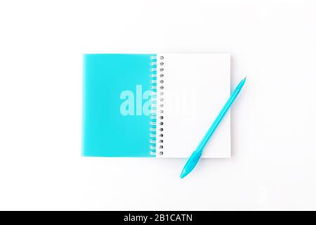 Top view of opened light blue cover spiral notepad with pen on white desk background. Mockup for your design. Flat lay. Stock Photo