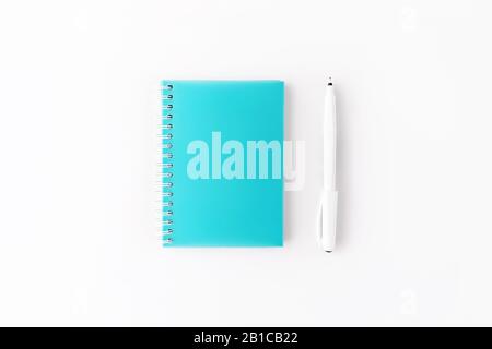 Top view of light blue cover spiral notepad with pen on white desk background. Mockup for your design. Flat lay. Stock Photo