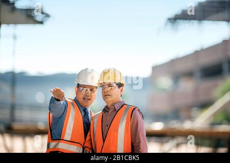 Workers at construction site discuss progress. Stock Photo