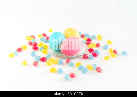 Bright creative Easter decoration of colorful eggs on white background decorated with jelly candies. Mockup for your design. Copy space. Stock Photo