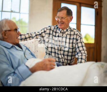 Smiling senior man visiting his friend in his bedroom. Stock Photo