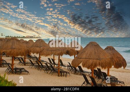 Chaise Lounges Under Straw Thatched Umbrellas on a Beach Stock Photo