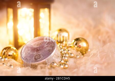 New Year's toys on white fur. Lantern, gold beads, gift box and disco balls. Christmas composition. Stock Photo