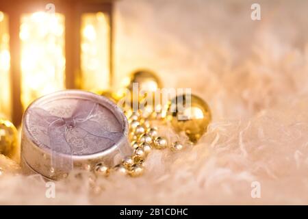 New Year's toys on white fur. Lantern, gold beads, gift box and disco balls. Christmas composition. Stock Photo