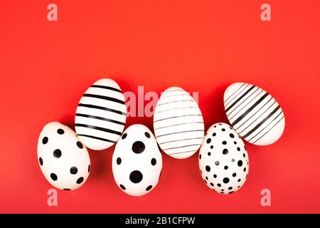 Different graphic hand-painted eggs on bright red background. Easter concept. Flat lay style. Stock Photo