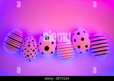 Different graphic hand-painted eggs in Proton Purple neon light. Easter concept. Top view. Stock Photo