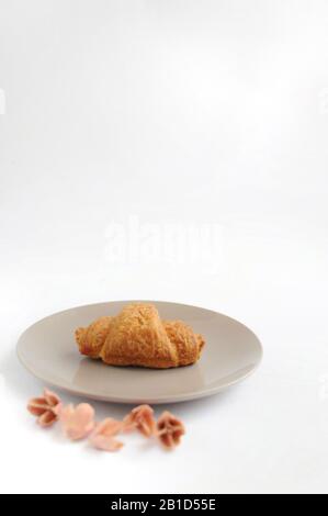Little croissant on the plate with decorated flowers on white background Stock Photo