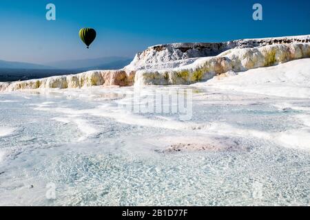 Travertine terrace formations at Pamukkale, tourists and hot-air balloon Stock Photo