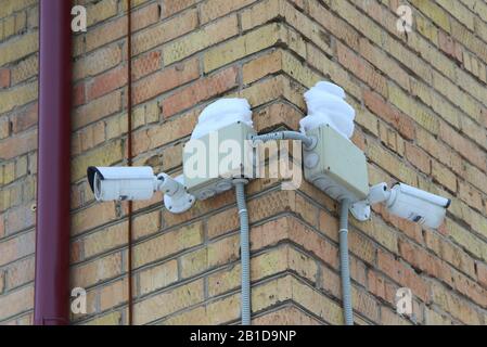 Surveillance camera mounted on brick wall of house. Security concept, tracking system, monitoring and control. Stock photo for web and print with empty space for text. Stock Photo