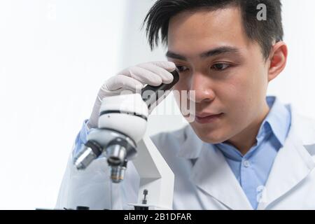 Kind young researcher looking through a microscope Stock Photo