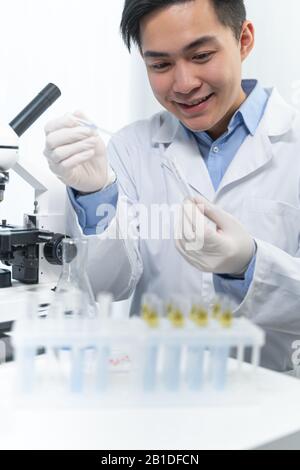 Pleased young Asian scientist inventing antiviral vaccine Stock Photo